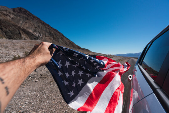 USA, California, Death Valley, man's hand holding American flag besides car