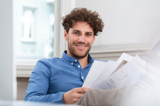Smiling businessman holding document in office