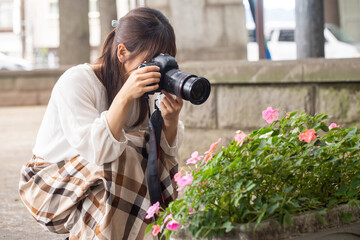 Fototapeta na wymiar 公園で写真を撮る女の子 カメラを楽しむカメラ女子 花の写真を撮る女性