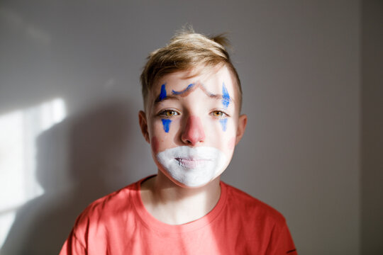 Portrait of sad boy made up as a clown