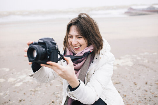 Portrait of relaxed woman taking photos on the beach with camera