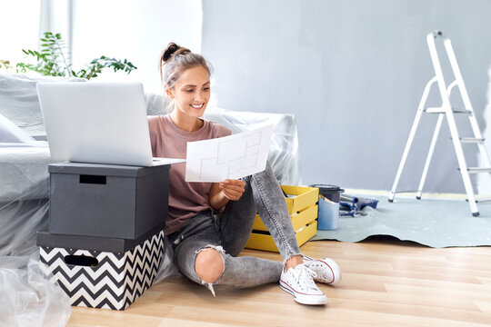 Young woman holding paper while working on laptop at home