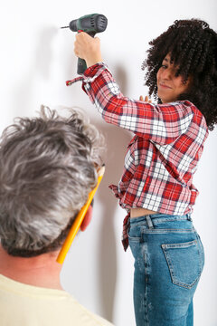 Couple drilling hole in the wall at home