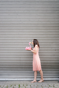 Woman in summer dress with heart pattern, kkissing pink flamingo figure