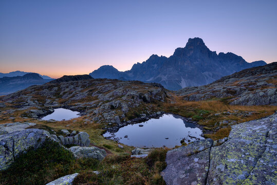Italy, Dolomites, Pale di San Martino Mountain group with mountain peak Cimon della Pala and two small mountain lakes at sunrise
