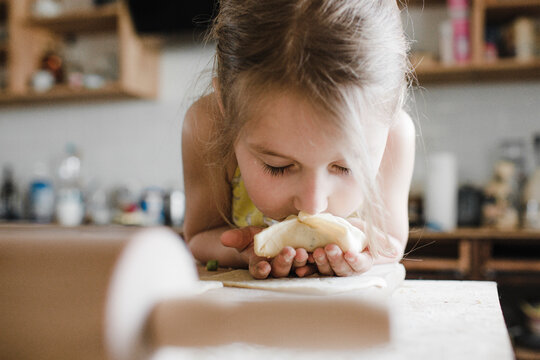 Little girl smelling freshly prepared stuffed pastry