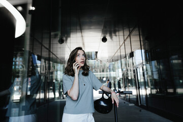 Woman with e-scooter and helmet using smartphone in a passage