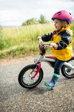 Toddler girl with pink cycling helmet on balance bicycle