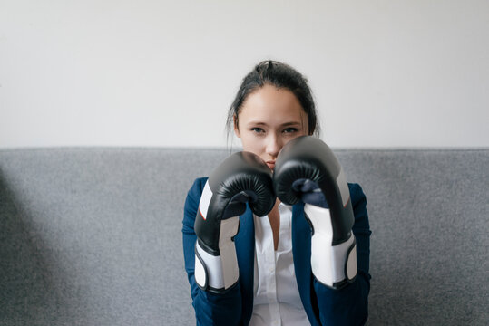 Portrait of young woman on couch wearing boxing gloves