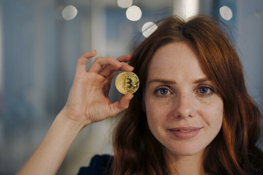 Portrait of redheaded woman holding bitcoin