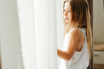 Little girl with long hair by the window