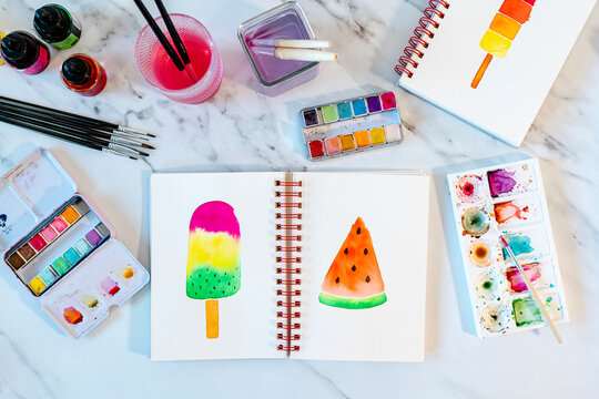 Ice cream bar and watermelon slice painted in book on marble table