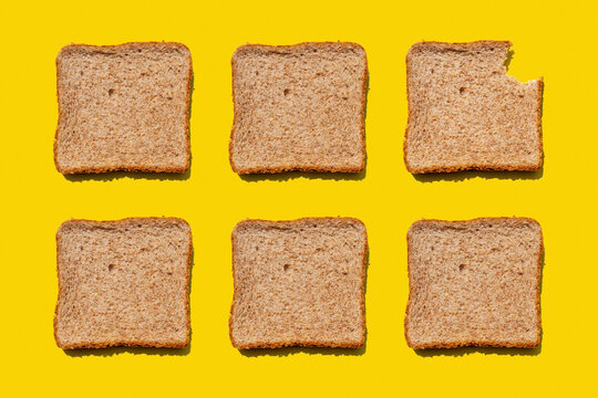Studio shot of six slices of wheat bread against yellow background