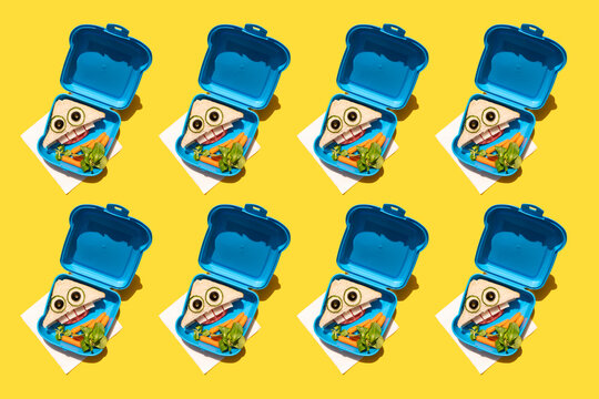 Pattern of lunch boxes with baby carrots and funny looking sandwiches with anthropomorphic faces