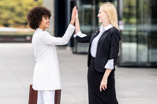 Business people greeting with giving high-five while standing outdoors