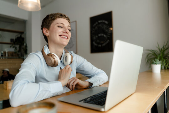 Happy businesswoman with laptop and headphones in a cafe