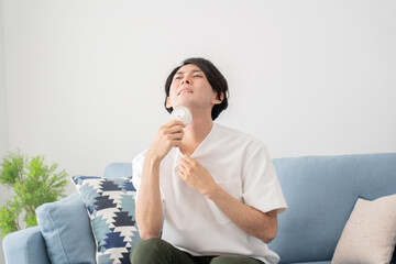 ハンディ扇風機で涼む若い男性・熱中症対策
