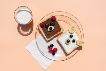 Studio shot of glass of milk and toasts with bear faces made of fruits