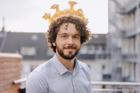 Portrait of confident businessman on roof terrace wearing a crown