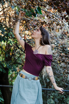 Portrait of young woman touching leaves of tree in park