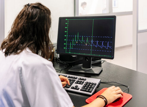 Female doctor analyzing line graph over computer in hospital