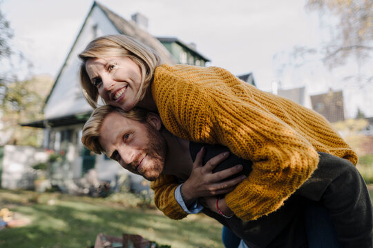 Man giving his wife a piggyback ride in garden