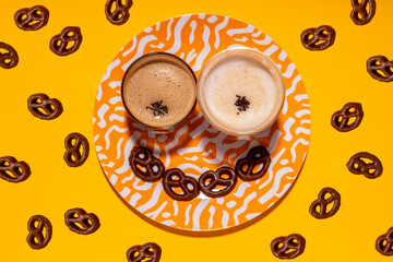 Anthropomorphic face made of plate, chocolate pretzels and two glasses of coffee