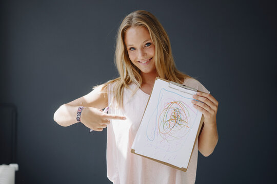 Portrait of blond young woman holding paper with scribbling