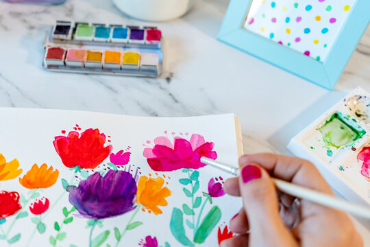 Woman painting botanic plants and flowers with watercolor on paper