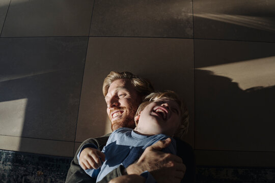 Happy father and son cuddling on the floor at home
