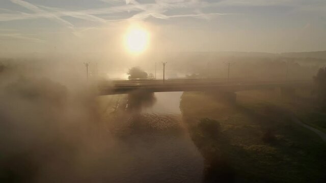 Backlit foggy empty bridge over ruhr river golden dawn. aerial drone crane shot
