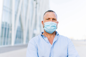 Mature businessman wearing protective face mask in city