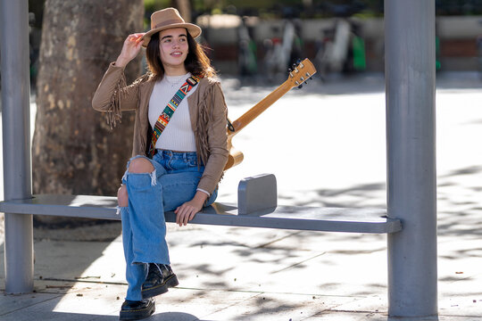 Beautiful woman sitting at bus stop during sunny day