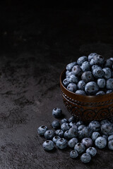 Fresh juicy blueberries in the bowl on the black background. Low key photography