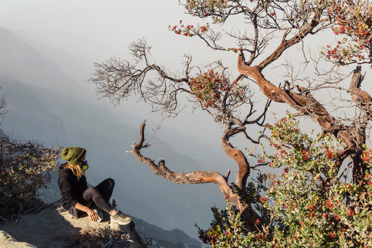 Woman with respirator mask sitting at volcano Ijen, Java, Indonesia