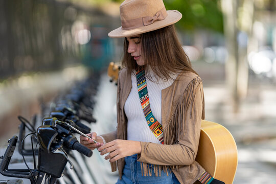 Young woman paying through smart phone at bicycle parking station