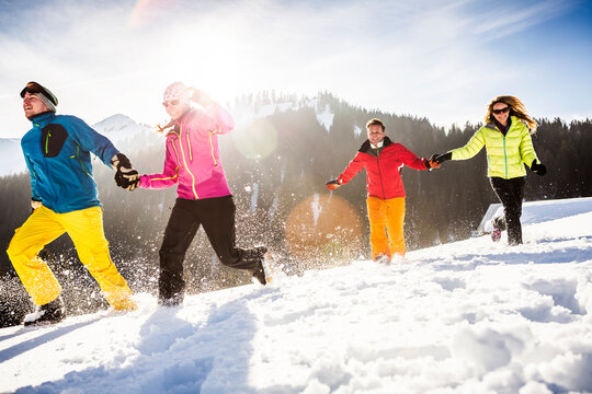 Group of carefree friends running and having fun in snow, Achenkirch, Austria