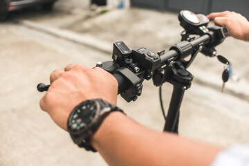 A man drives an electric scooter. Closeup of hands and handlebars.