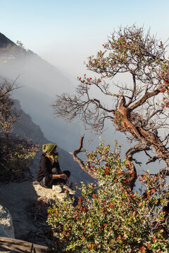 Woman with respirator mask sitting at volcano Ijen, Java, Indonesia