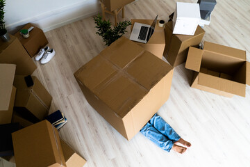 Man half covered in cardboard box while lying down in new house