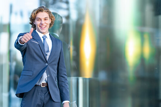 Happy male entrepreneur doing thumbs up sign against glass