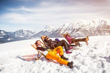 Friends sunbathing in deck chairs in mountainscape in winter, Achenkirch, Austria
