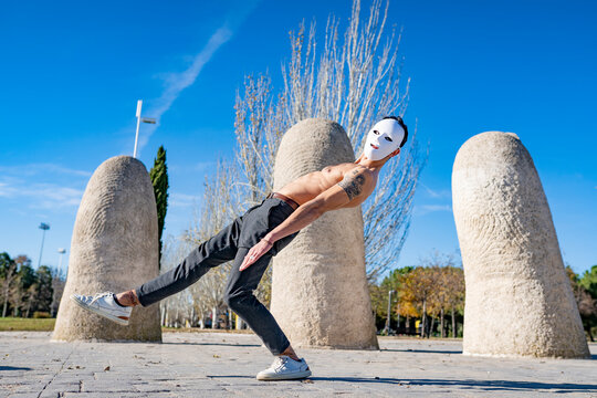 Man wearing white mask dancing while standing on footpath