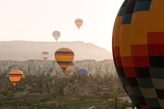 Colorful hot air balloons flying over mountains at Goreme National Park during sunset, Cappadocia, Turkey