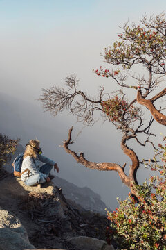 Woman with respirator mask sitting at volcano Ijen, Java, Indonesia