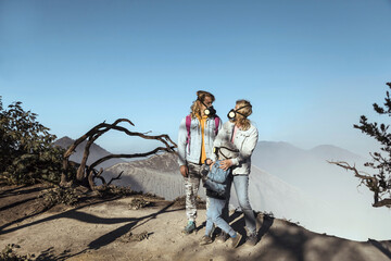 Family with respirator masks standing at the edge of volcano Ijen, Java, Indonesia