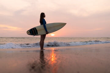 Young woman with surfboard at the beach, Kedungu beach, Bali, Indonesia