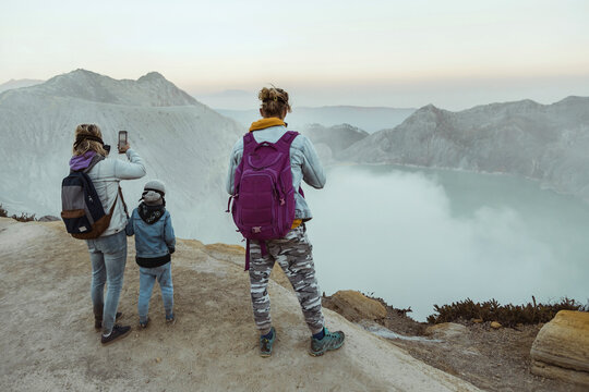 Family with respirator masks standing at the edge of volcano Ijen, Java, Indonesia