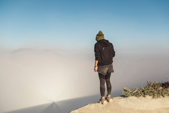 Young woman standing at the edge of volcano Ijen, Java, Indonesia