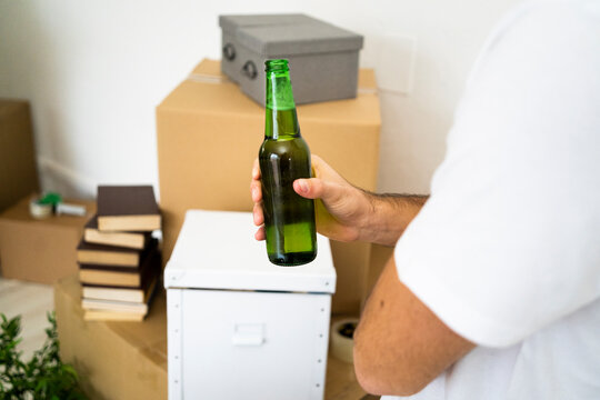 Man holding beer bottle while taking a break from moving in new apartment